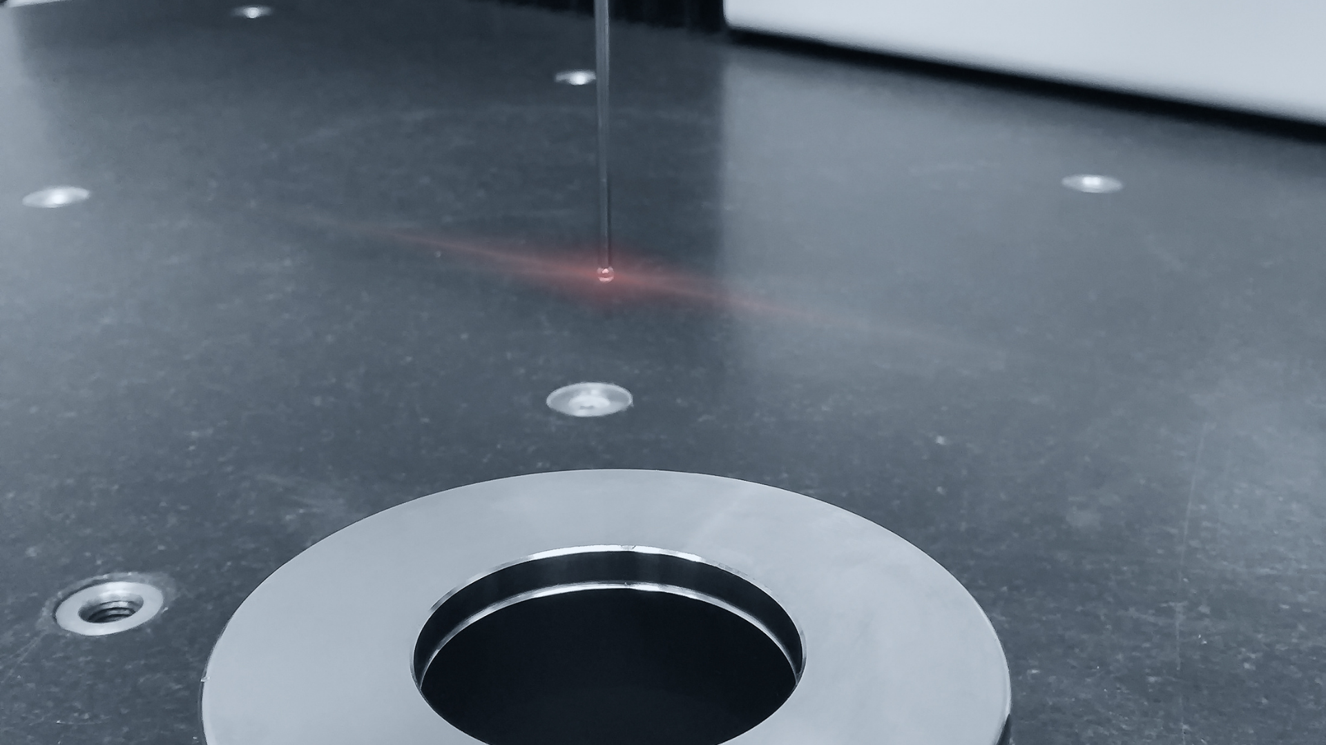 Laser cutting metal sheet, with bright orange sparks flying from the cutting head.