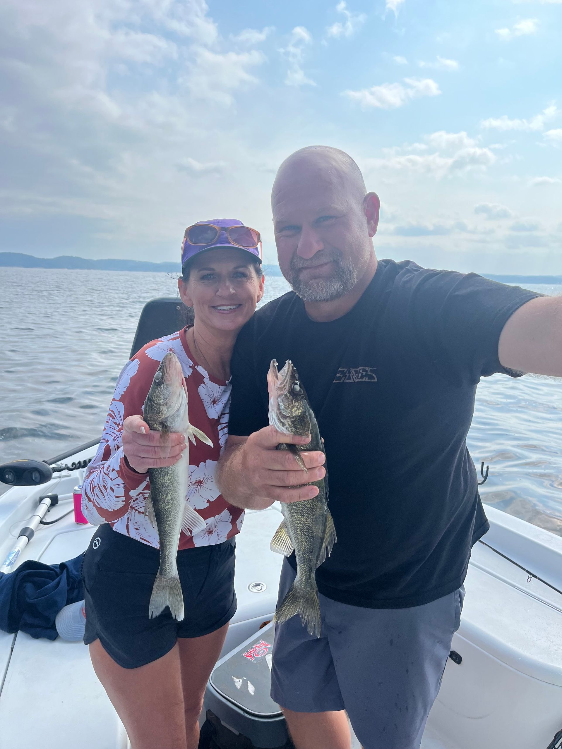 A man and a woman are holding fish on a boat.