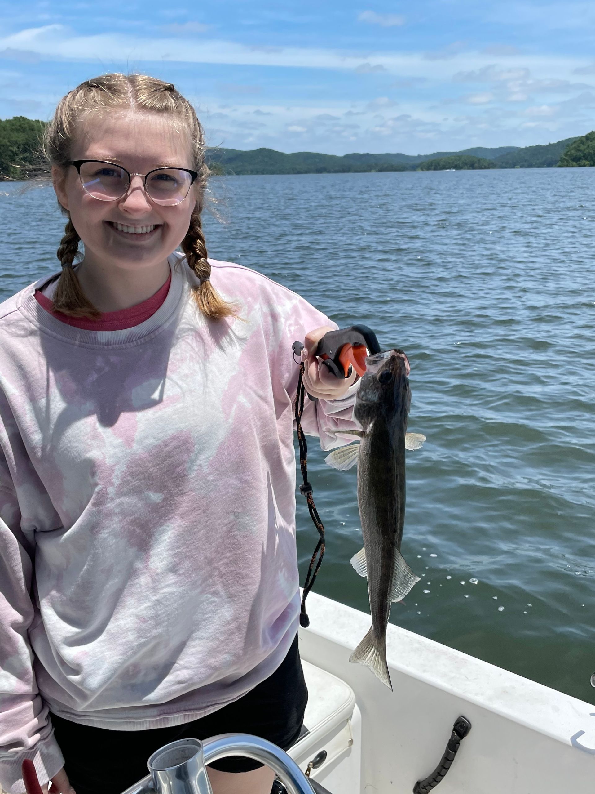 A young girl is holding a fish on a boat.