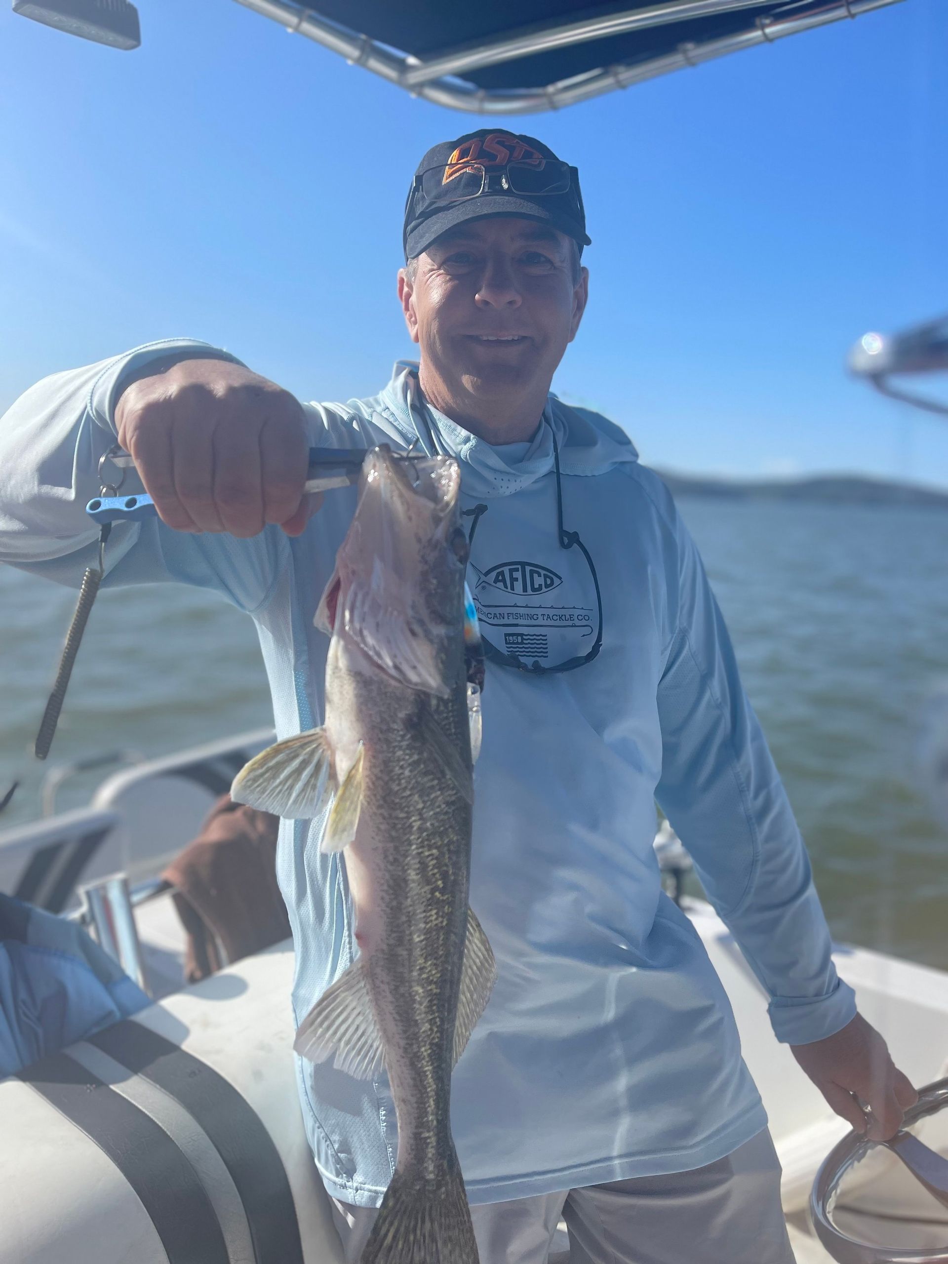 A man is holding a fish in his hand on a boat.
