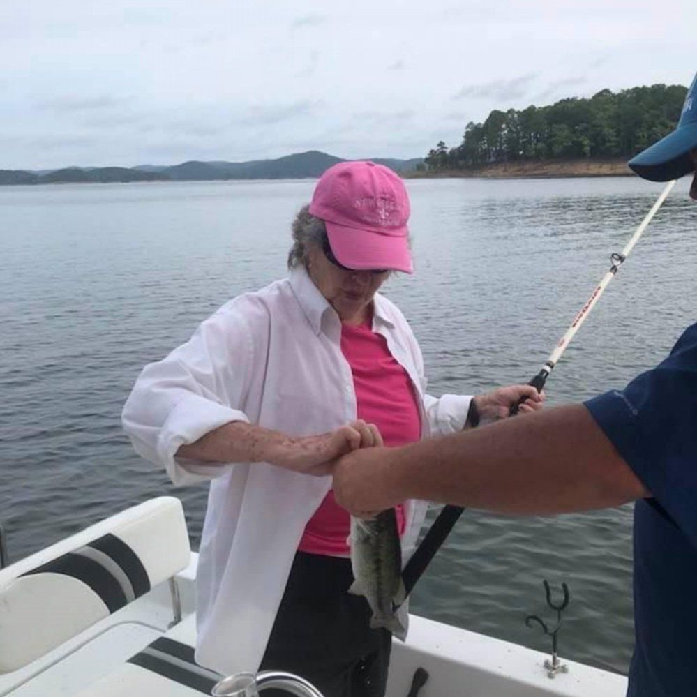 A woman in a pink hat is fishing on a boat
