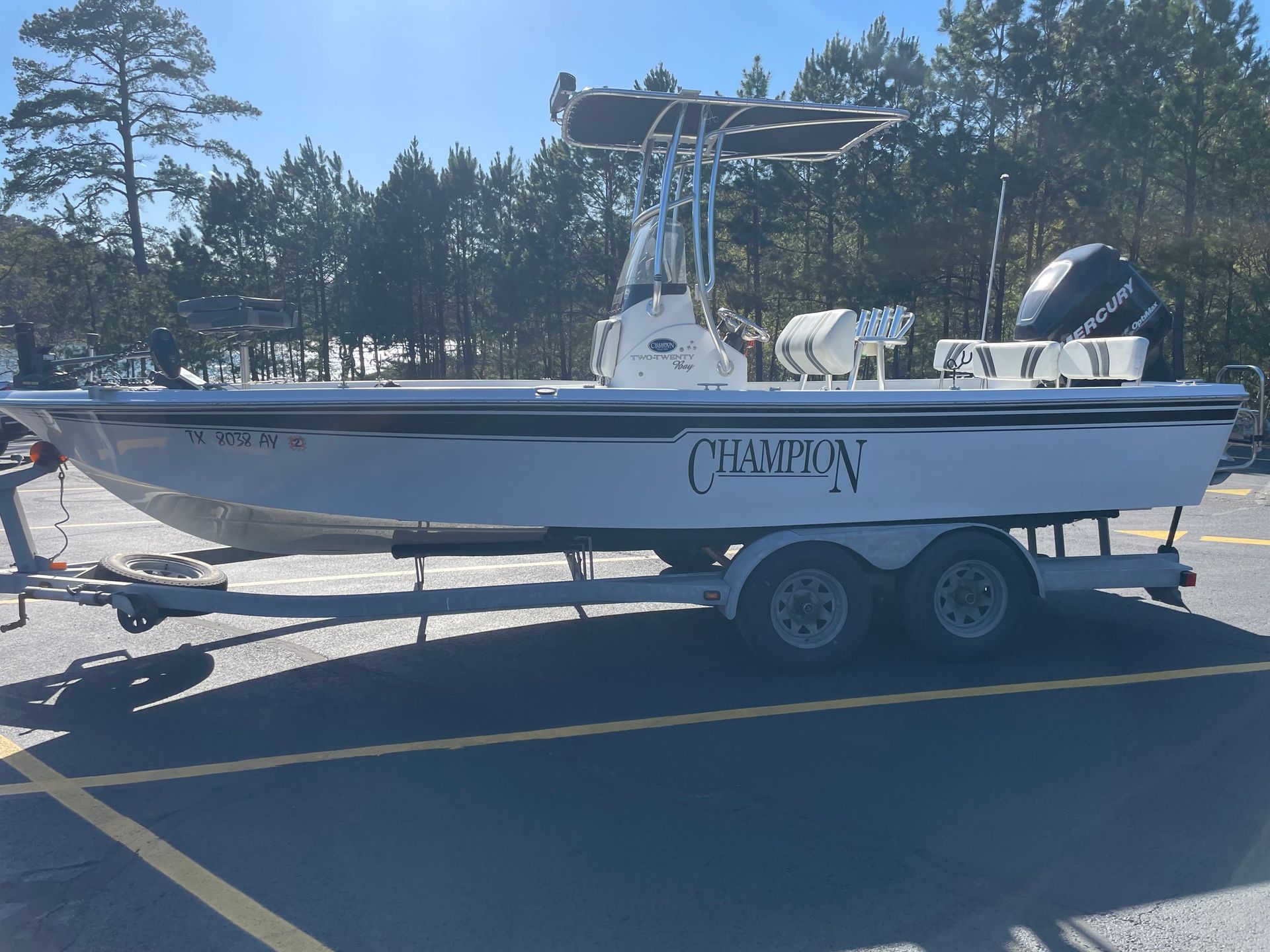 A white boat is parked on a trailer in a parking lot.