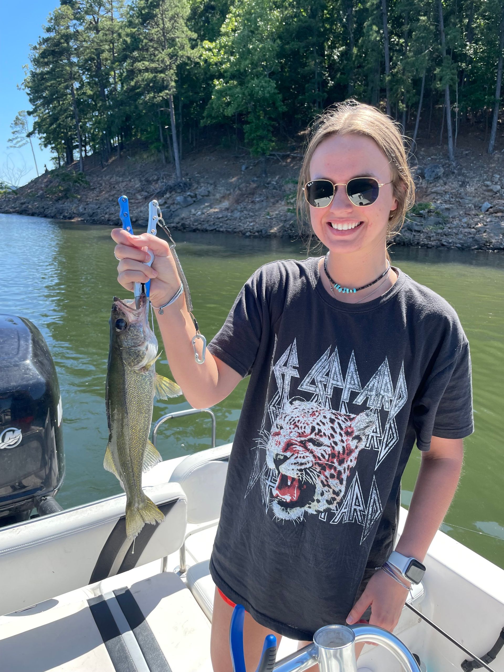 A woman is standing on a boat holding a fish.