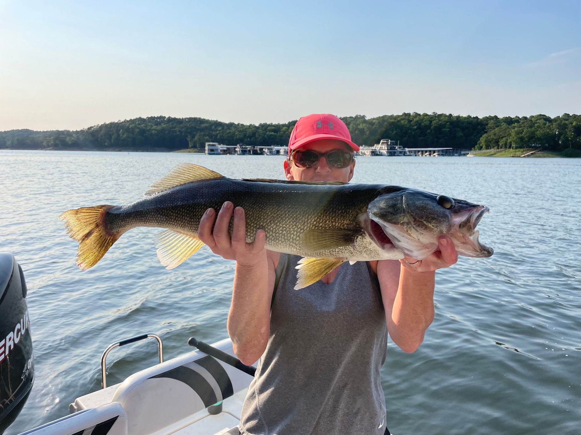 A man is holding a large fish on a boat.