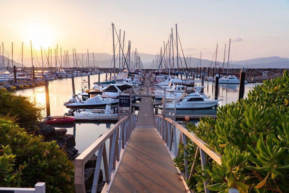 A Dock Leading To A Marina Filled With Boats At Sunset — FNQ Freight & Logistics In Port Douglas, QLD