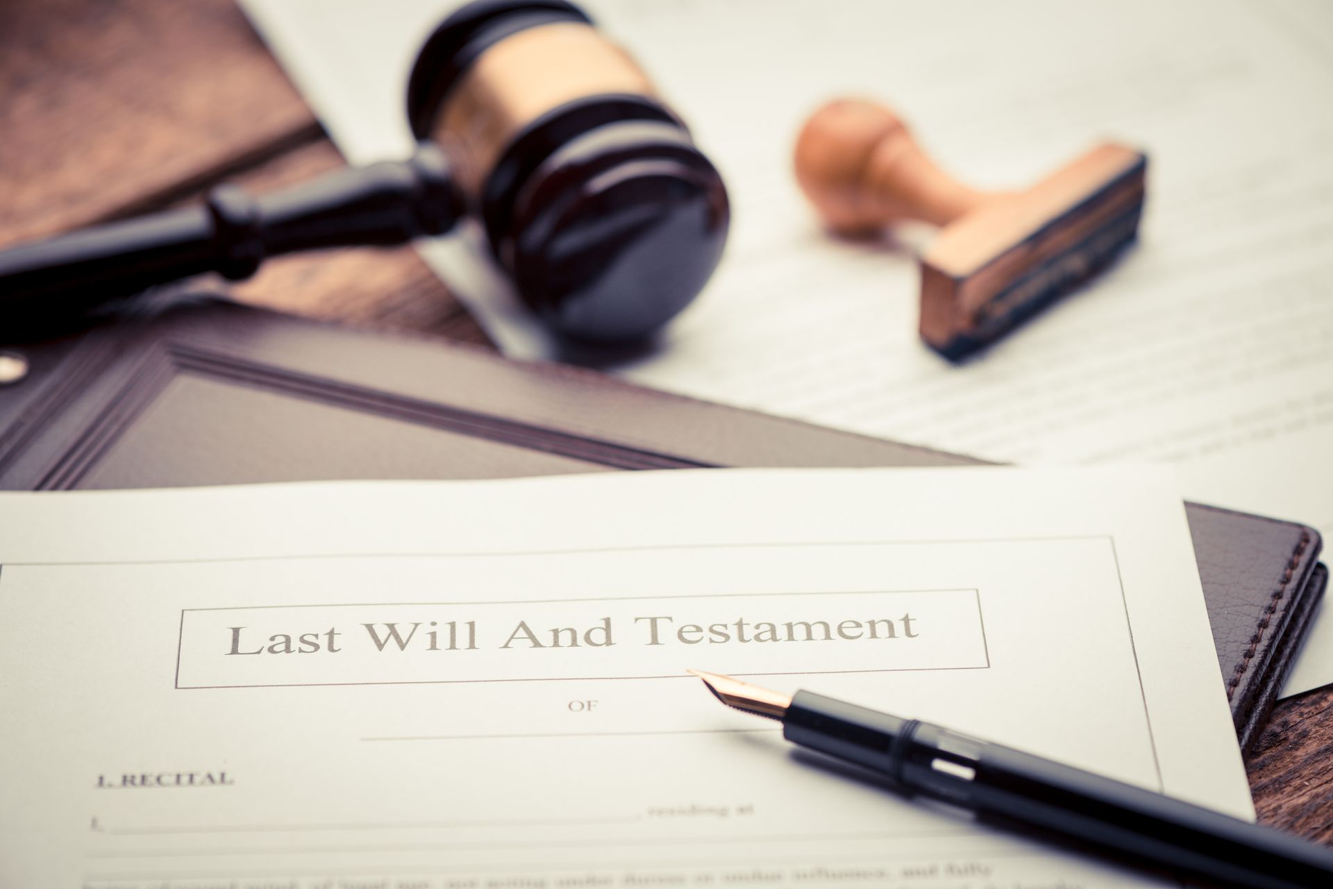 A last will and testament document with a fountain pen, judge's gavel, and notary stamp on a desk