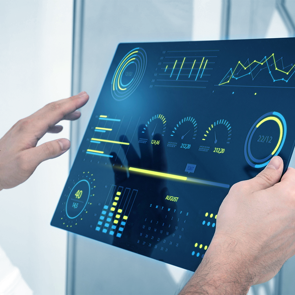 Hands holding a transparent screen displaying data visualizations with blue and yellow colors.