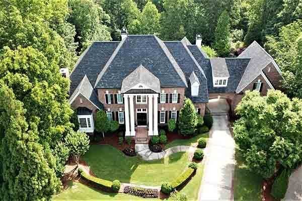 An aerial view of a large brick house surrounded by trees.