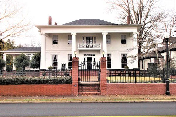 A large white house with a brick fence around it