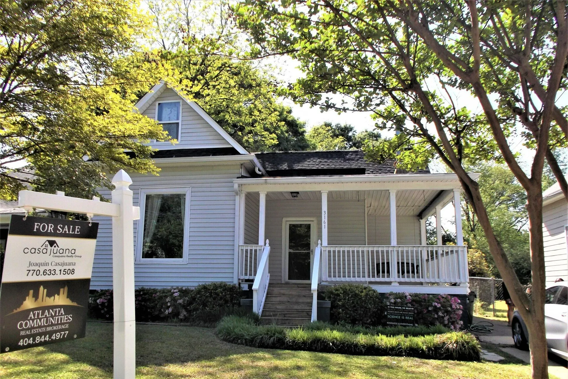 A white house with a sign in front of it that says for sale