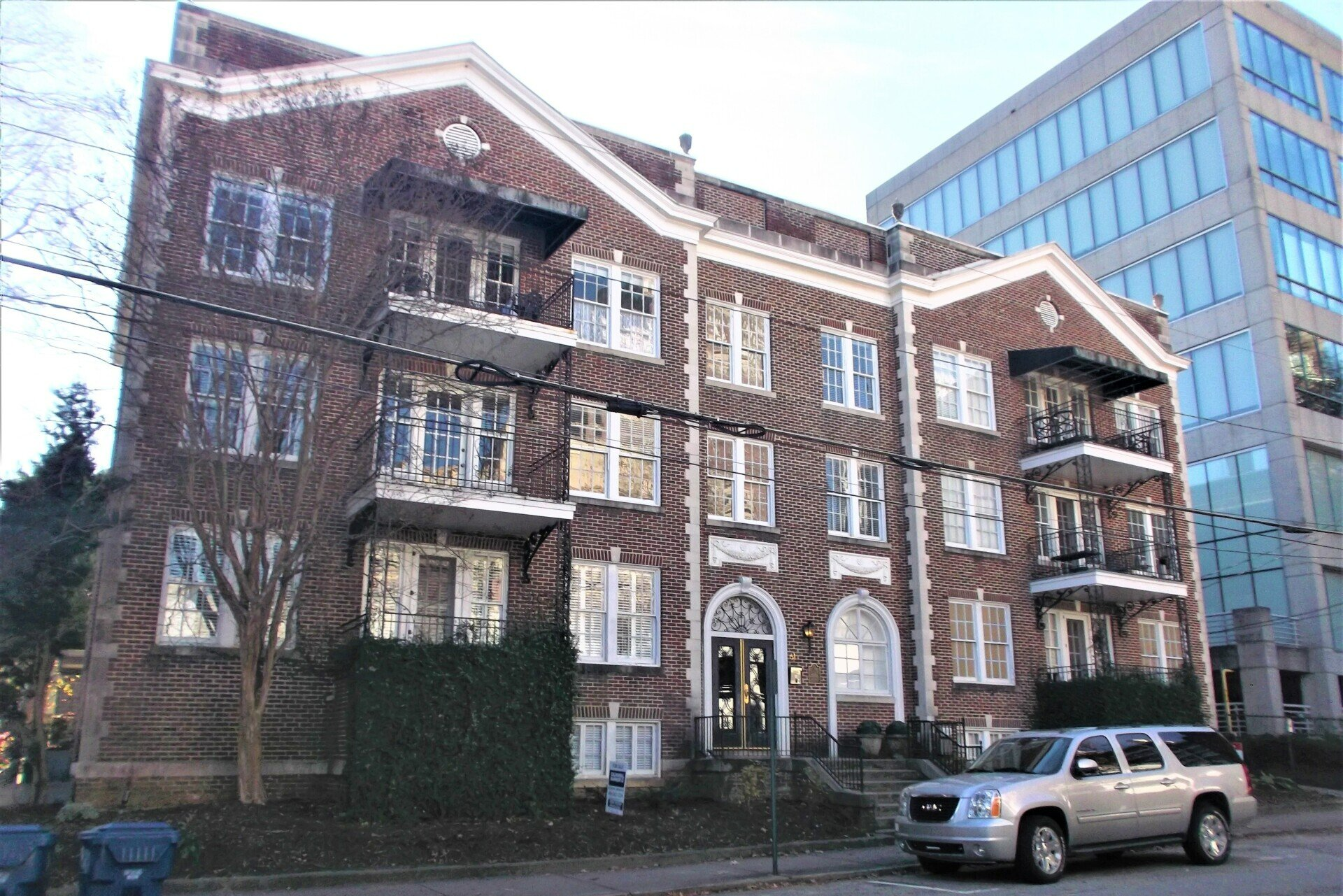 A silver suv is parked in front of a large brick building