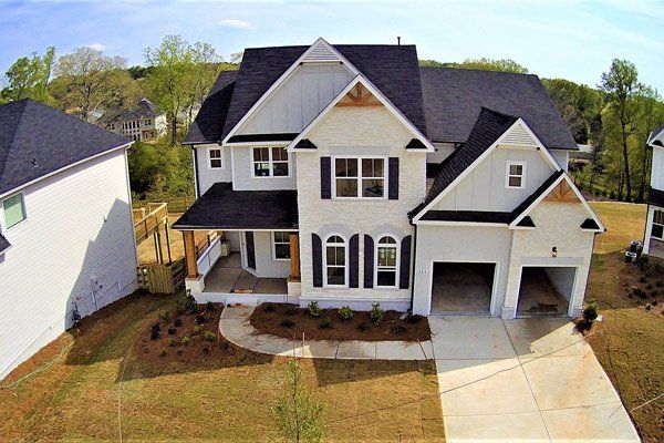 An aerial view of a large white house with a black roof.
