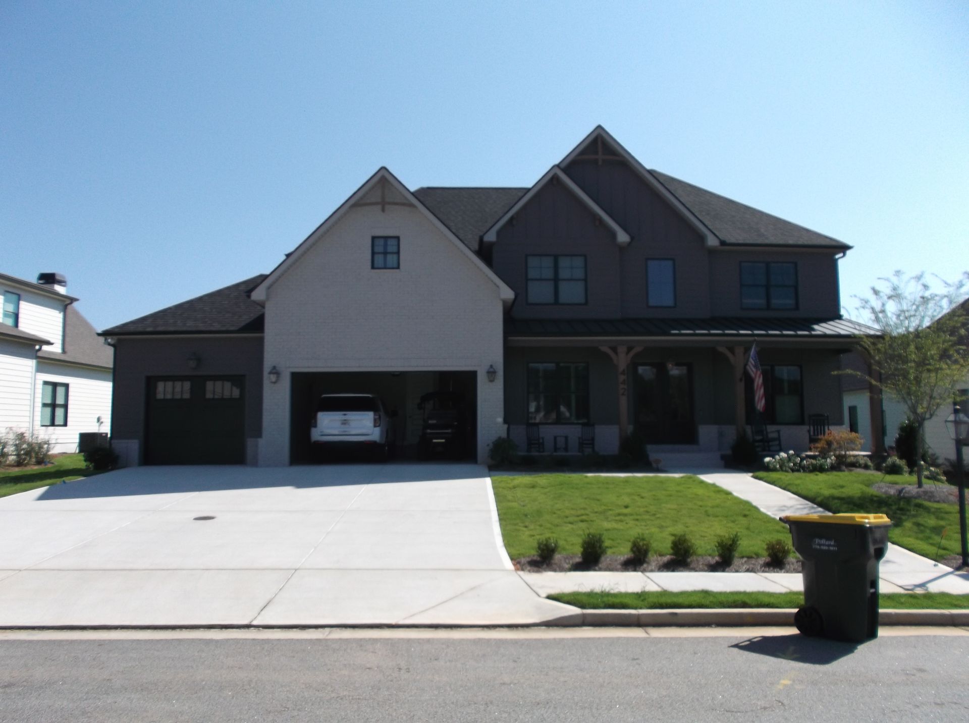 Suburban house with attached garage, driveway, and front lawn under a clear blue sky