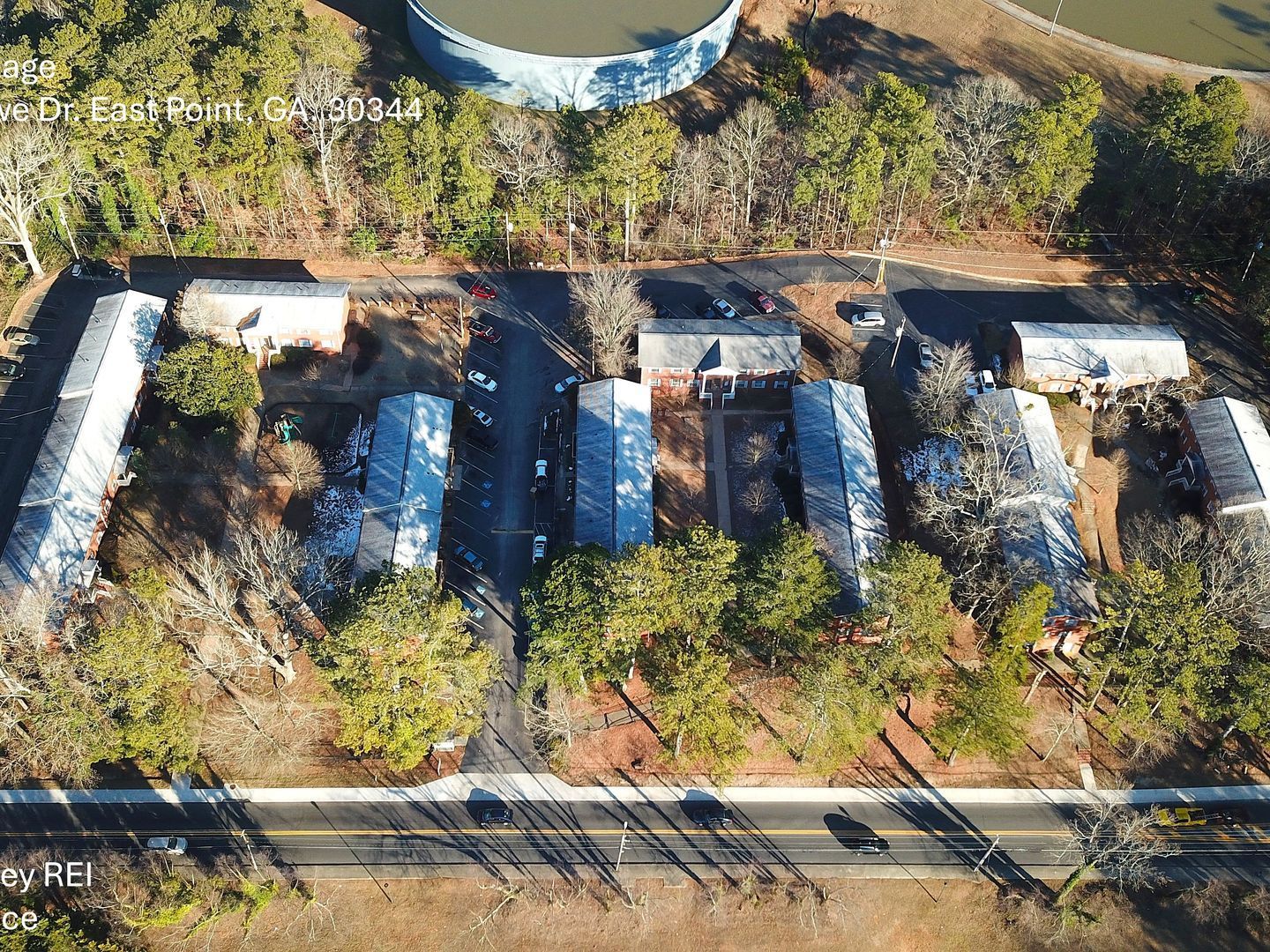 An aerial view of a row of houses surrounded by trees and a road.