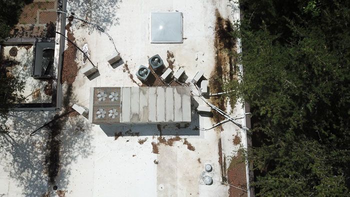 An aerial view of a roof with a lot of trees in the background.