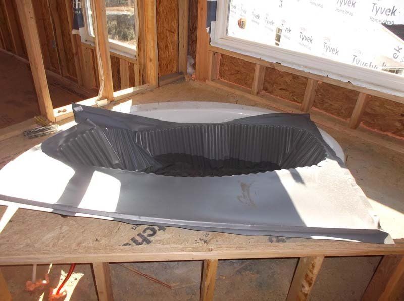 A bathtub is sitting on top of a wooden table in a building under construction.