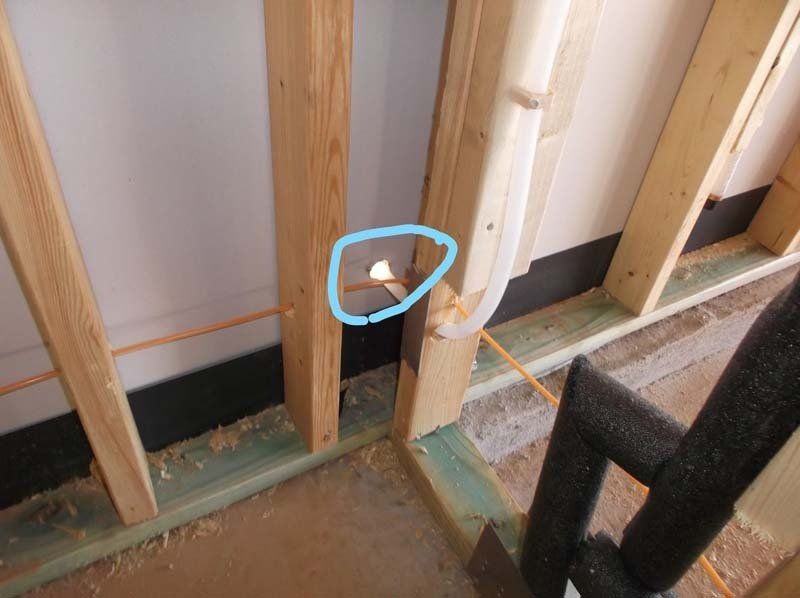 A wooden wall with a pipe coming out of it and a blue circle around it.