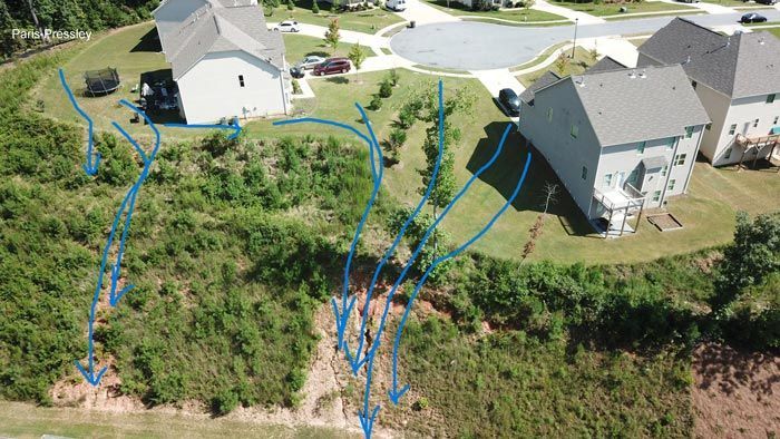 An aerial view of a residential area with houses and a slope.