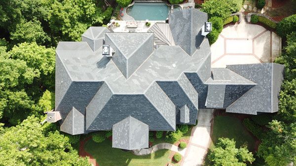 An aerial view of a large house with a pool in the backyard surrounded by trees.