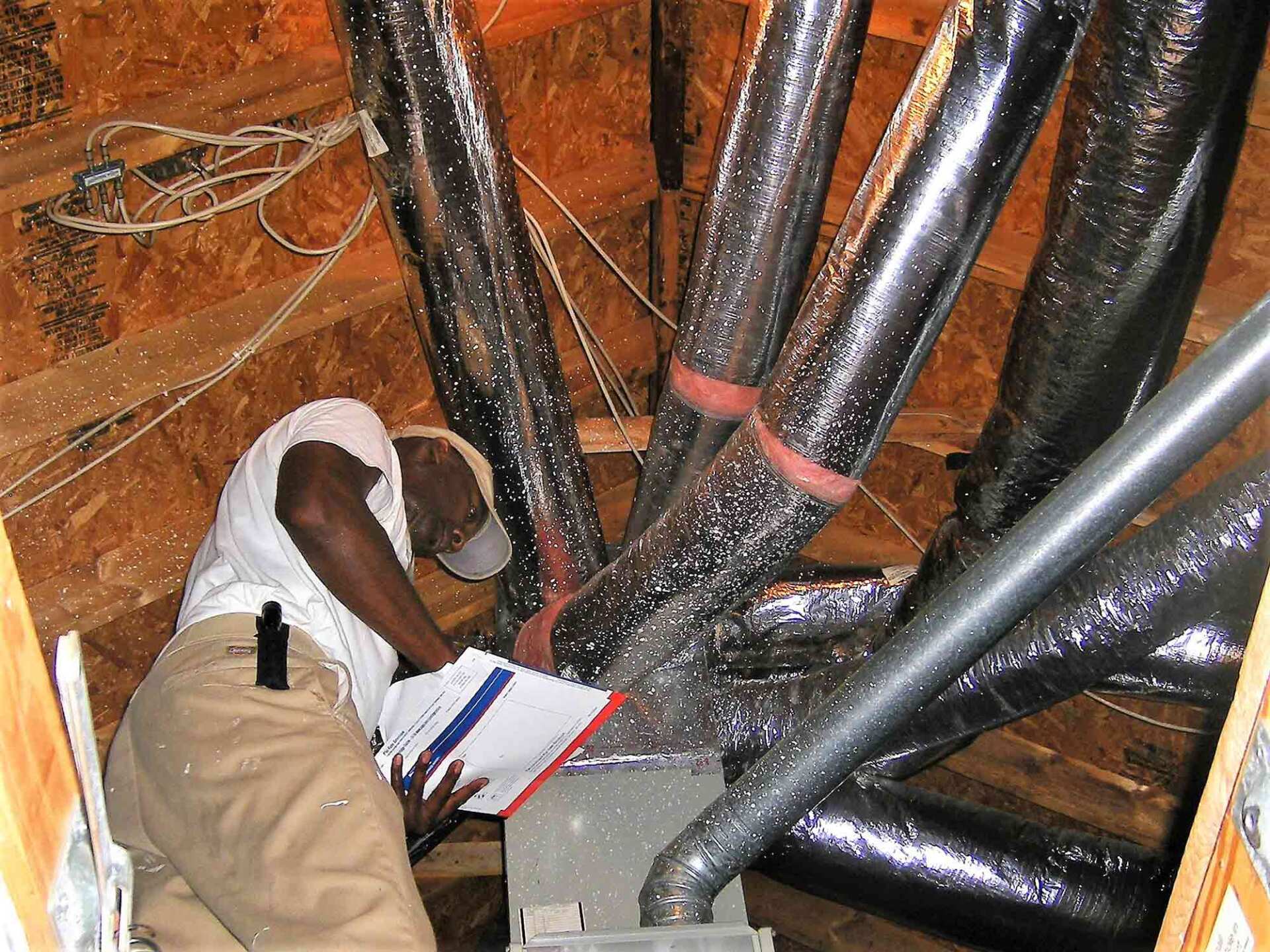 A man is looking at a piece of paper in a room with lots of pipes