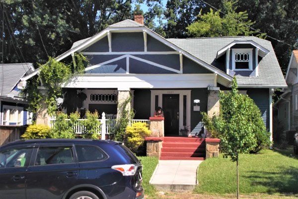 A blue car is parked in front of a house