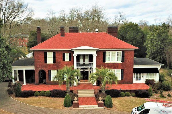 A large brick house with a red roof and a white van parked in front of it.