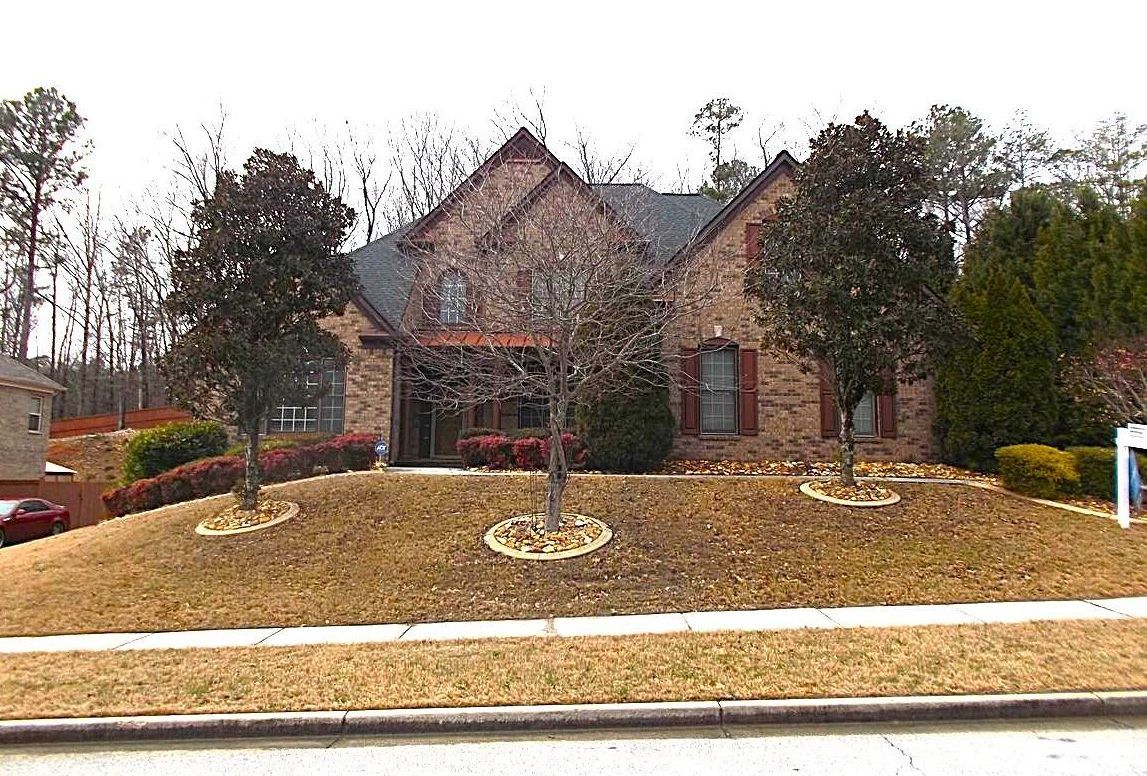 A large brick house with a lot of trees in front of it.