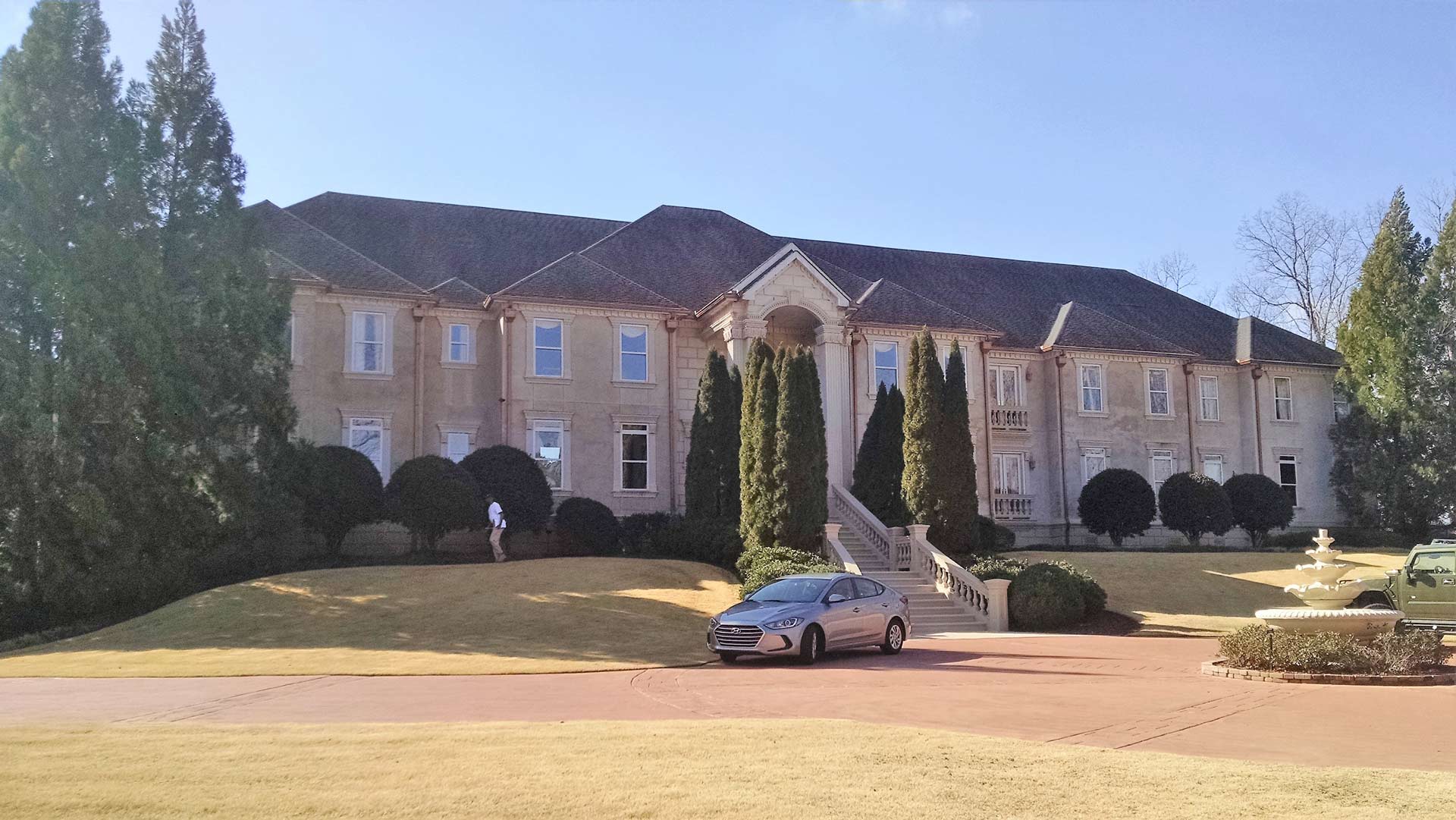A car is parked in front of a large house