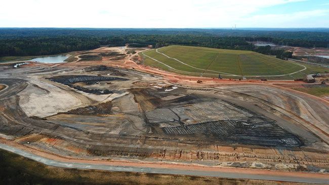 An aerial view of a large construction site in the middle of a forest.