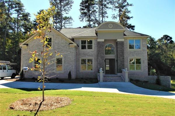 A large brick house with a white van parked in front of it