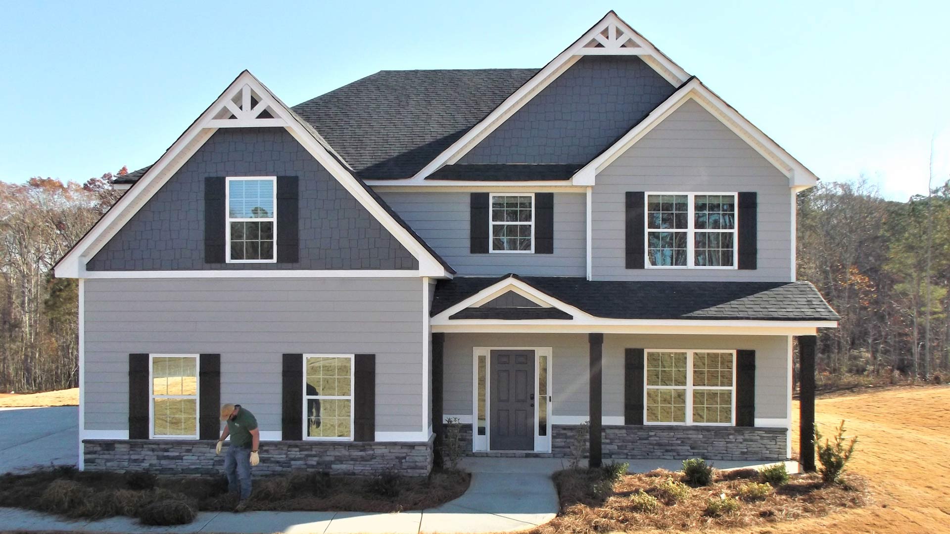 A man is standing in front of a large house