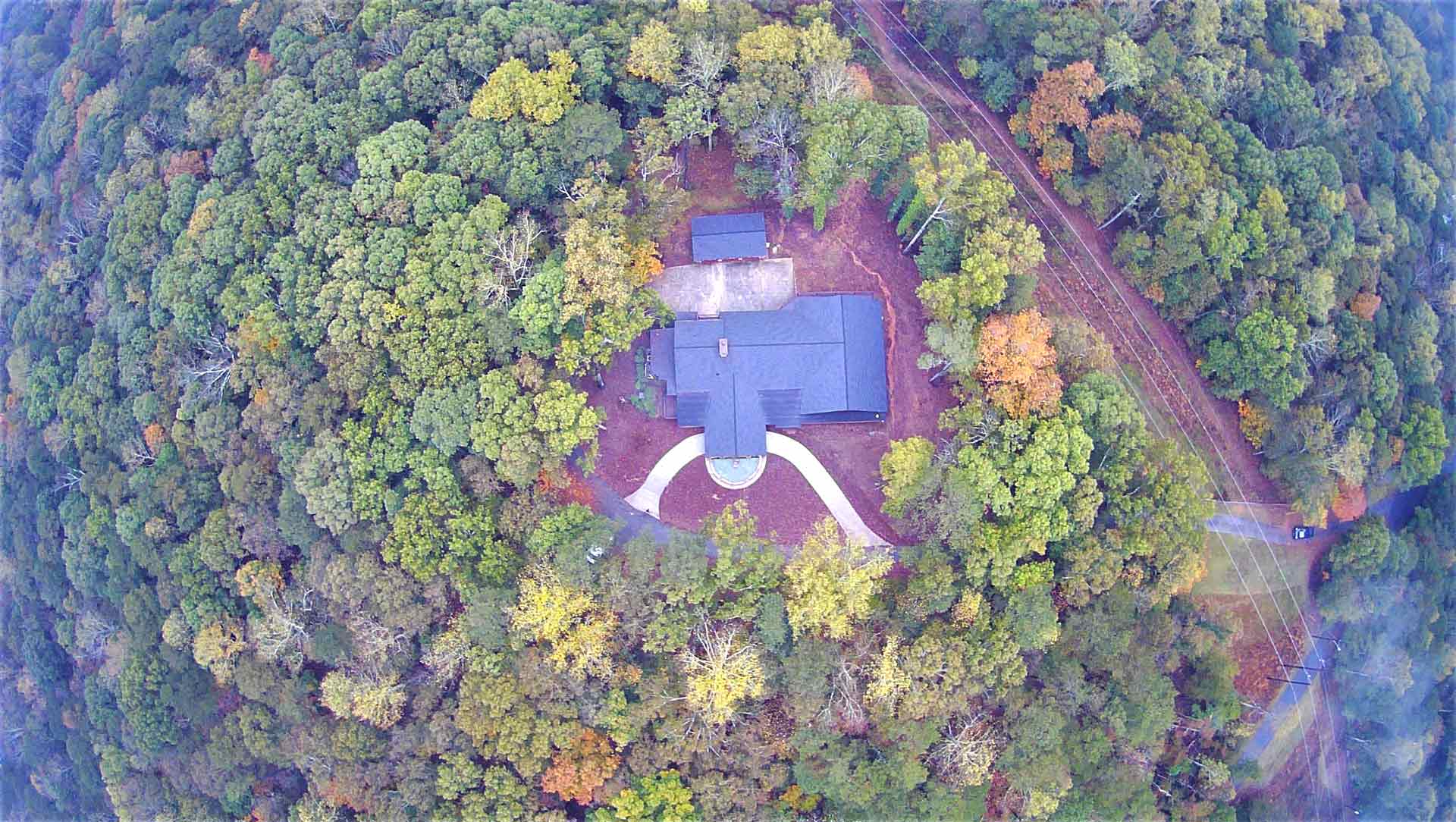 An aerial view of a house in the middle of a forest.