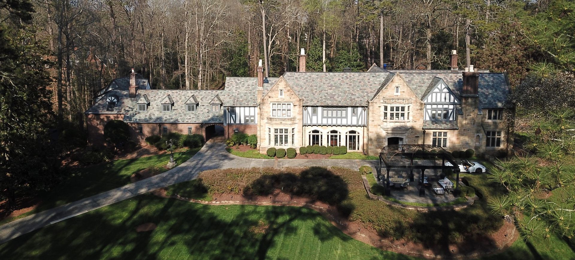 An aerial view of a large house in the middle of a forest.