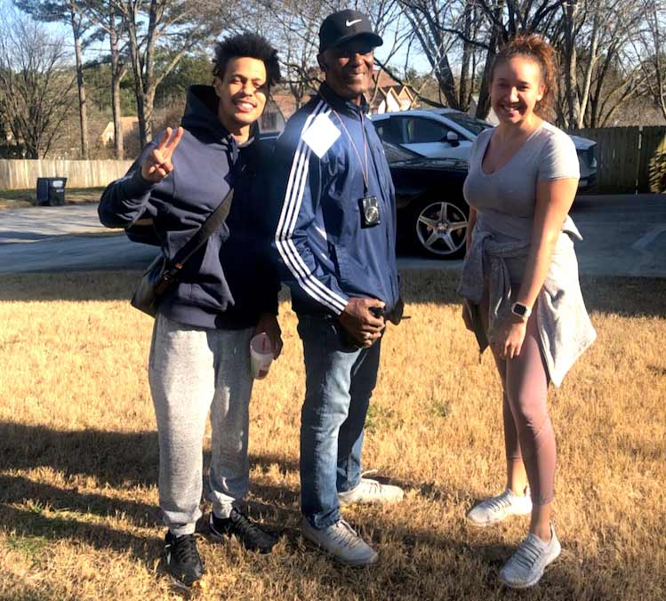 Three people are posing for a picture in a grassy field