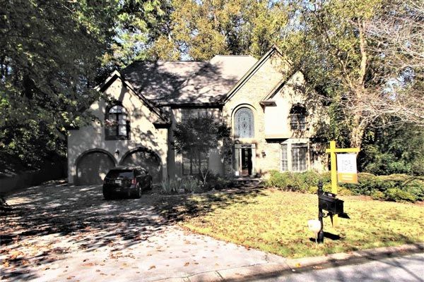A large house with a for sale sign in front of it.
