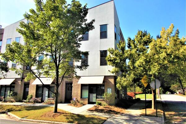 A large white building with a lot of windows and trees in front of it.