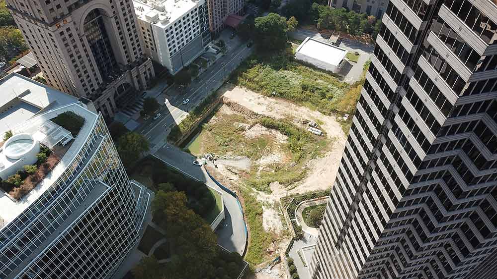An aerial view of a city with a lot of tall buildings and a lot of grass.