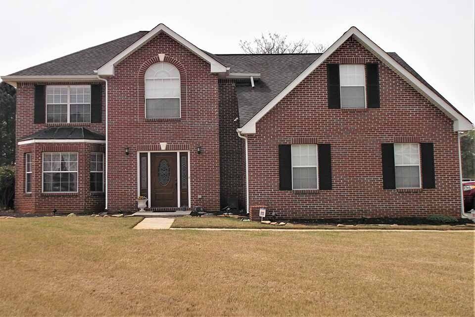 A large brick house with black shutters on the windows