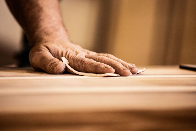 Pulizia manuale di una superficie di legno con un panno bianco.
