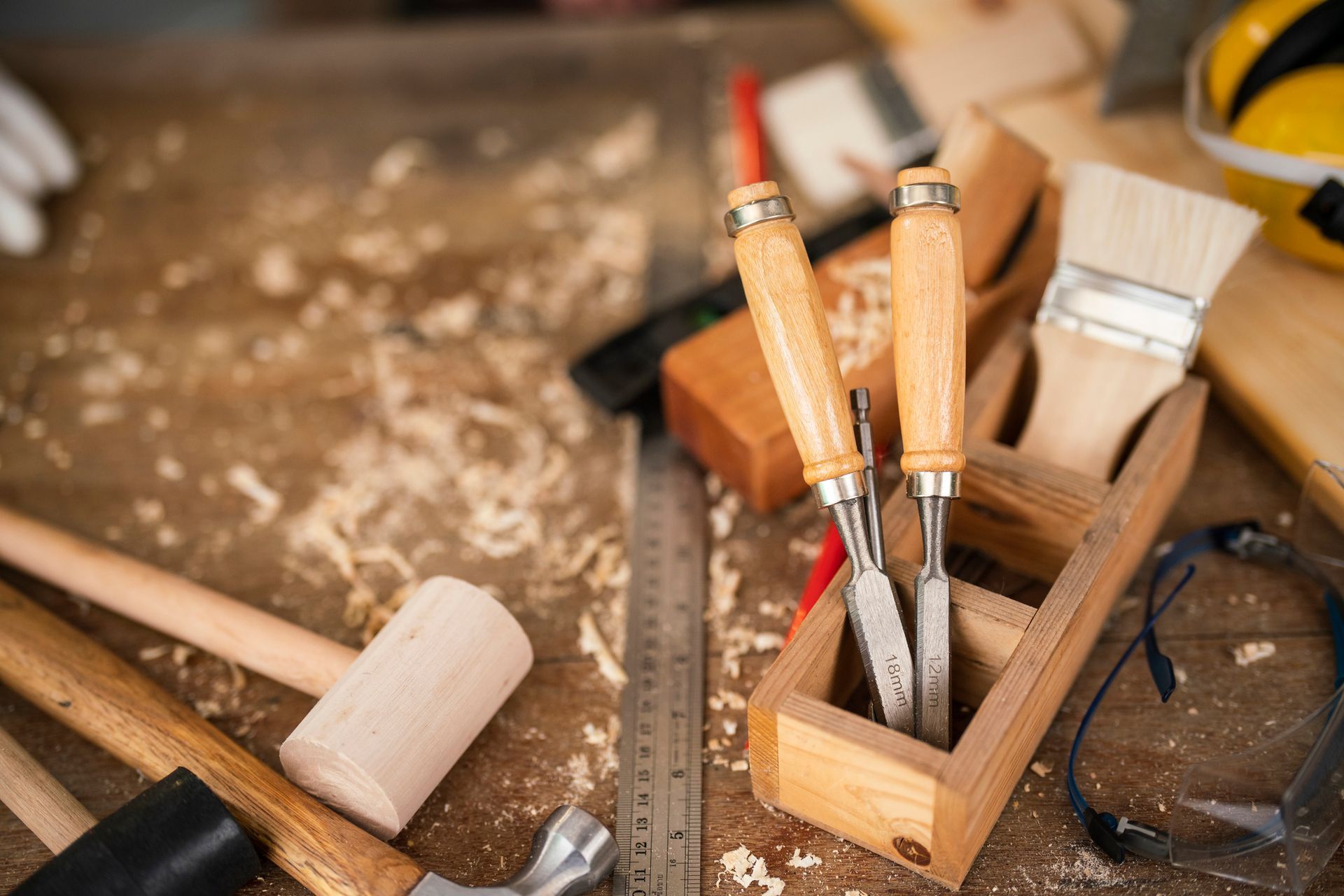Attrezzi per la lavorazione del legno e dispositivi di protezione su una superficie di lavoro in legno con trucioli di legno.
