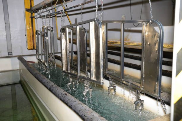 A row of metal objects are sitting in a tank of water.