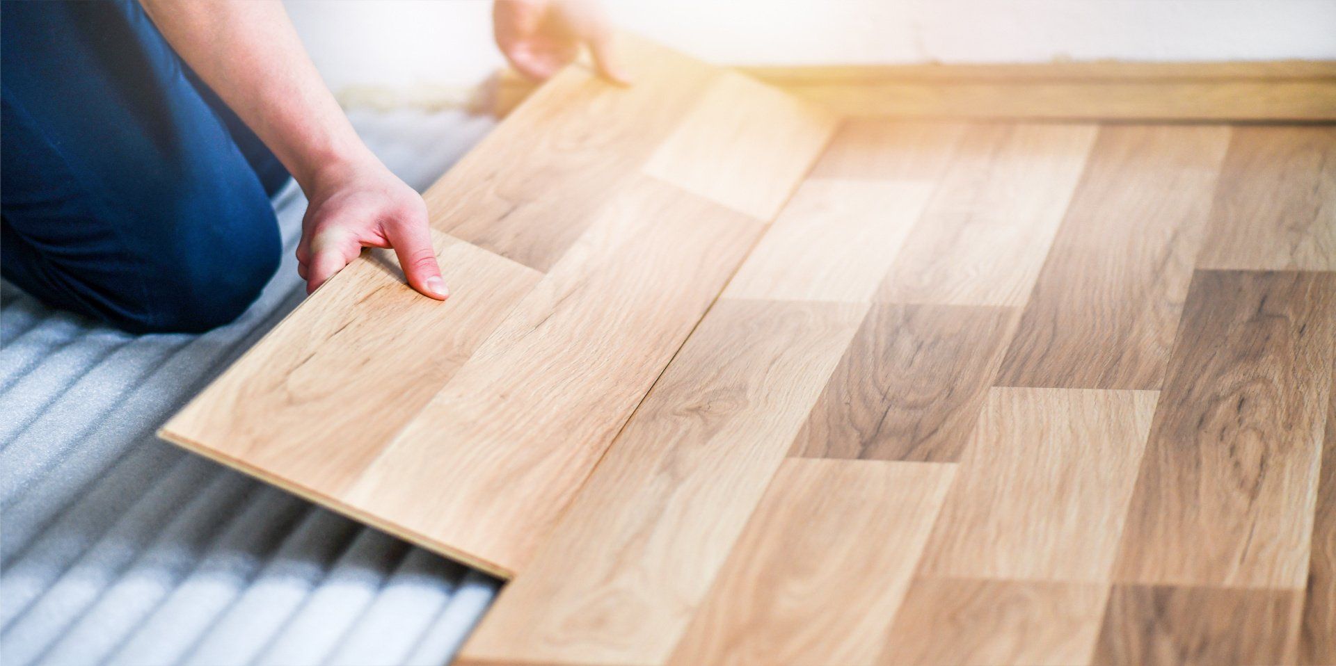 A person is installing a wooden floor in a room.