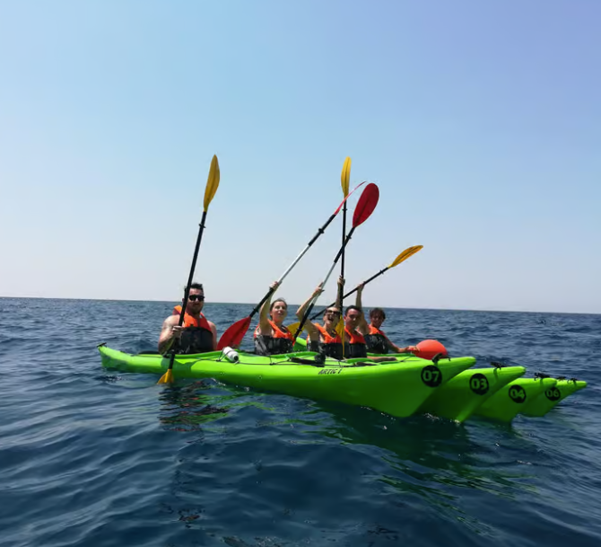 Quattro persone in kayak su un kayak biposto verde brillante in un mare aperto e calmo.
