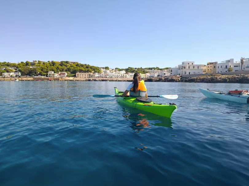 Gita in kayak su acque blu calme vicino a una costa di case sotto un cielo limpido.
