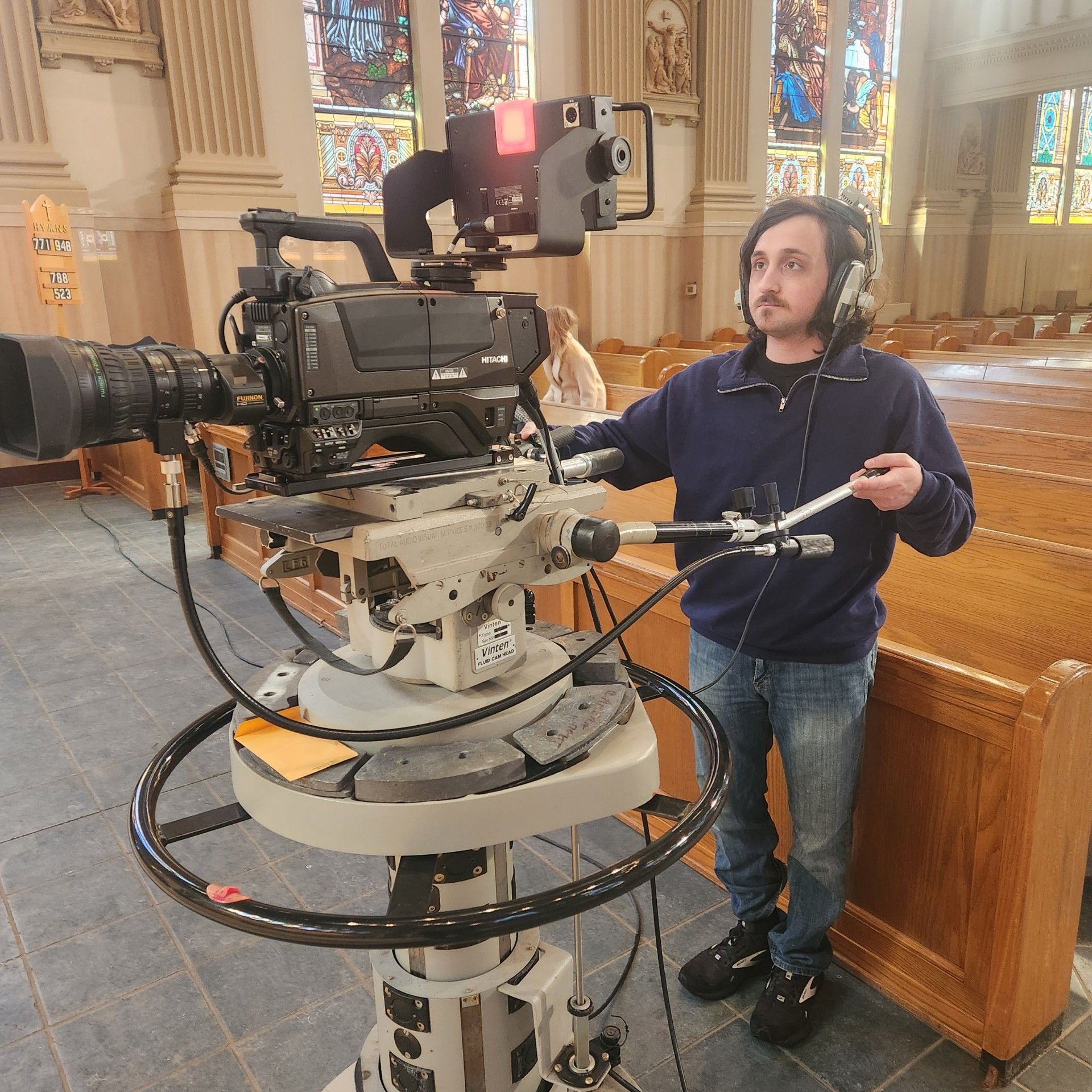 Volunteer camera operator with HD camera in front of cathedral for Proclaim TV Mass