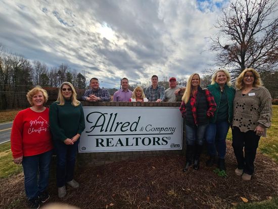 A group of people standing in front of a sign that says allred realtors