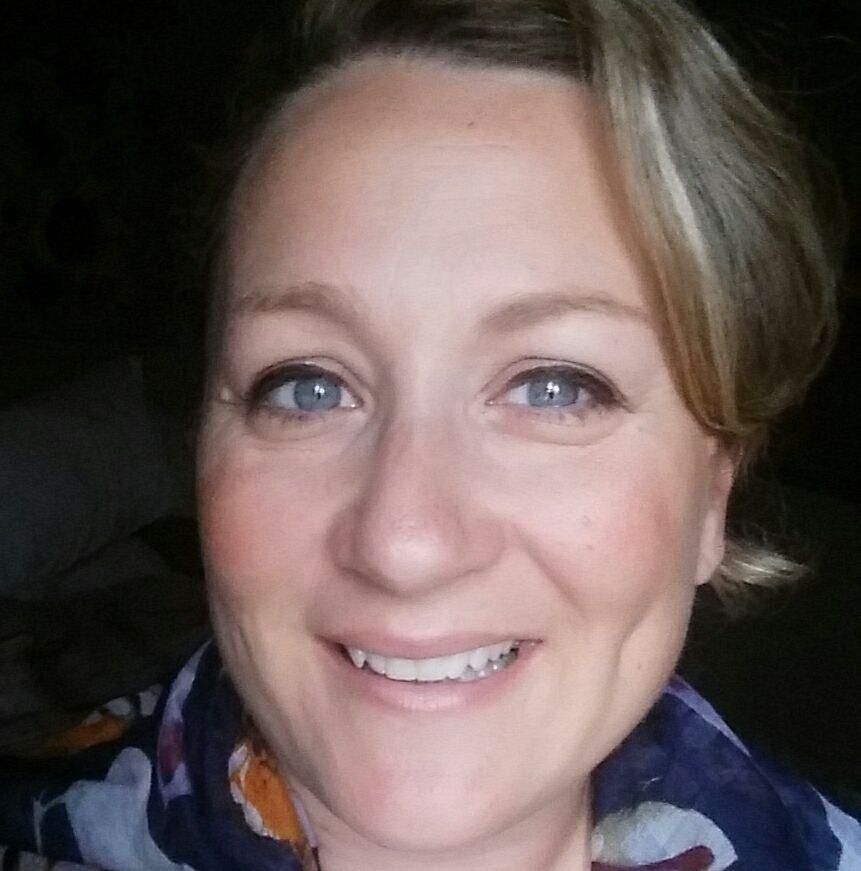 A woman is smiling and wearing a scarf around her neck