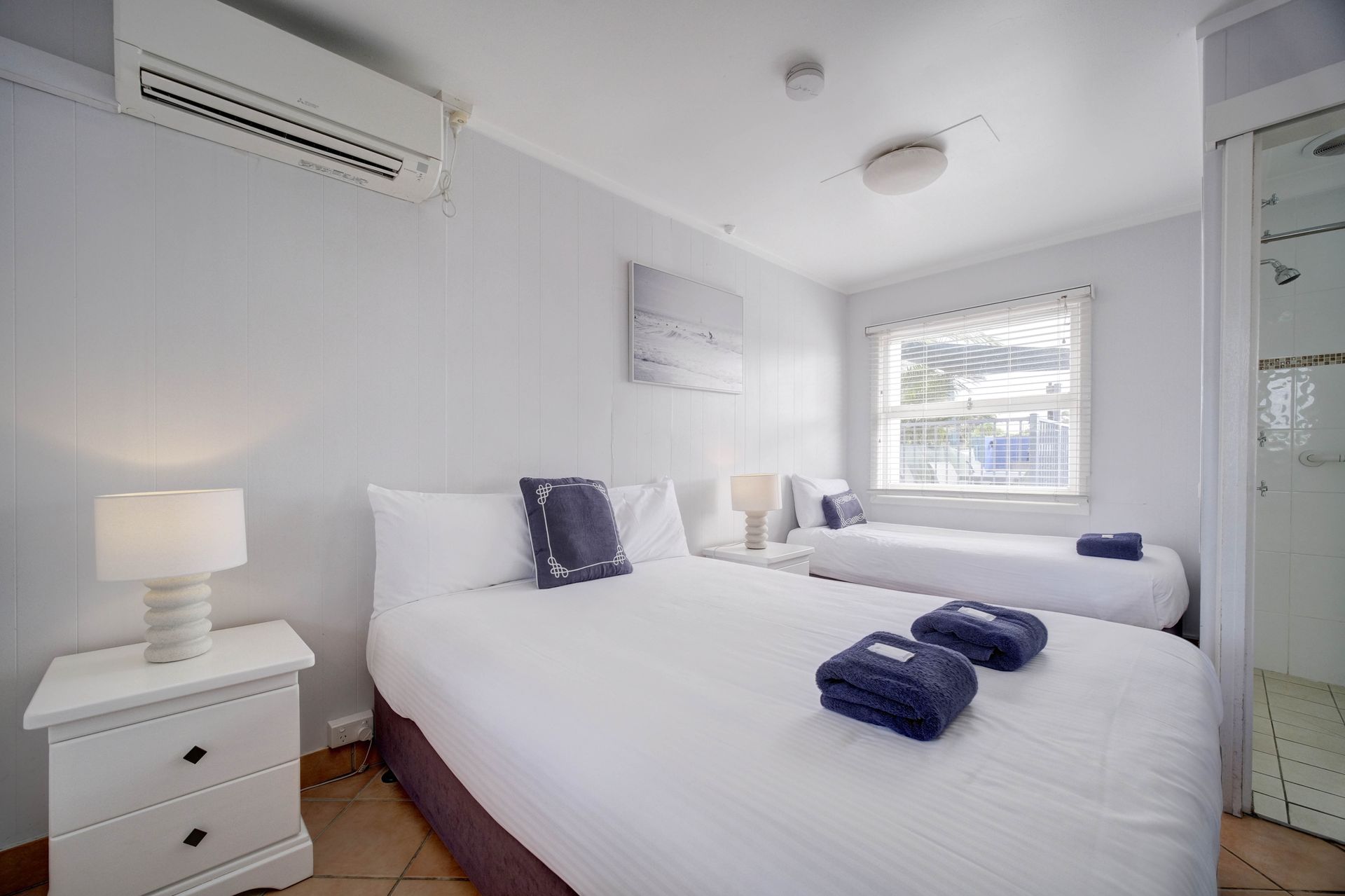 Bedroom with two beds, white linens, nightstands, and a window.