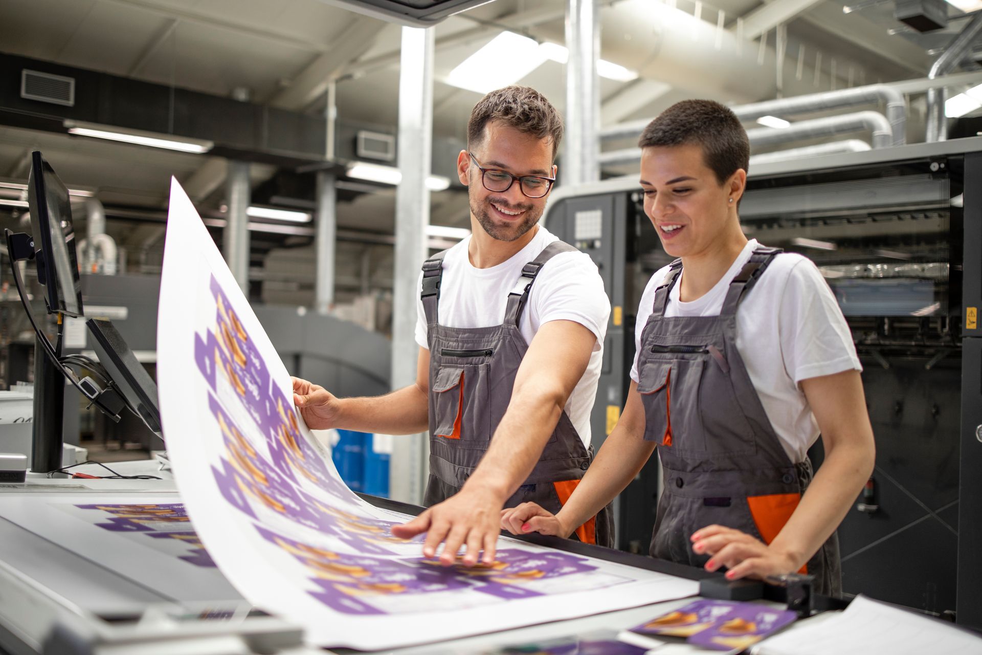 Two workers are checking the print quality in a modern print shop for business printing.