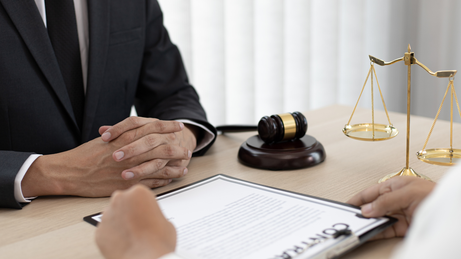 Lawyer’s desk with hands, gavel, scales of justice, and contract paperwork